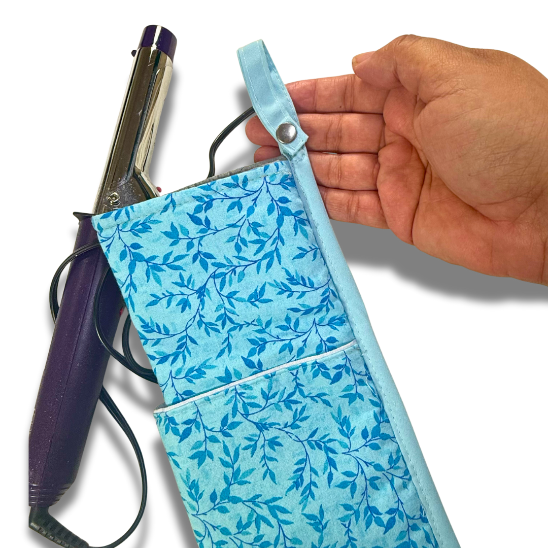 Hand holding a blue floral-patterned hair straightener case with a hair straightener inside.