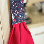 Red apron with a blue star pattern hanging on a hook.