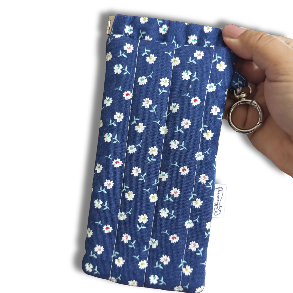 Blue White Daisies quilted Flexi Frame Pouch clipped to a black tote bag handle, holding sunglasses