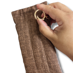Hand opening a gold round swivel hook on a brown pouch in a white solid background