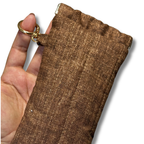 A close-up of a hand holding a brown textured sleeve or pouch with a gold-tone key ring attachment, shown against a plain white background.