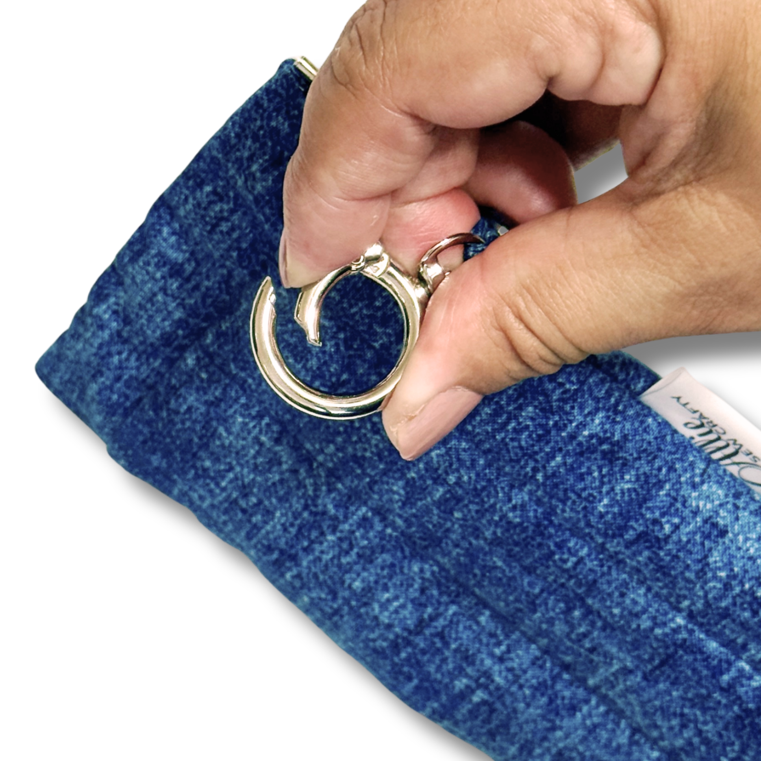 A close-up of a hand holding a silver metal key ring attached to a textured blue fabric pouch or sleeve against a white background.