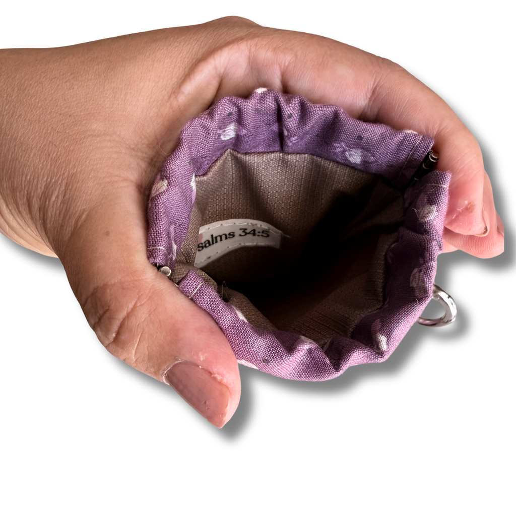 hand opening a snap on pouch showing the tan lining and tag that says Psalms 34:5