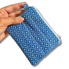 A hand holding a small zippered fabric pouch with a blue, white, and light blue geometric pattern, shown against a plain white background.
