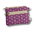 A purple quilted fabric wallet with a white floral pattern, featuring two zippered compartments, a card slot, and a keychain attachment in white background