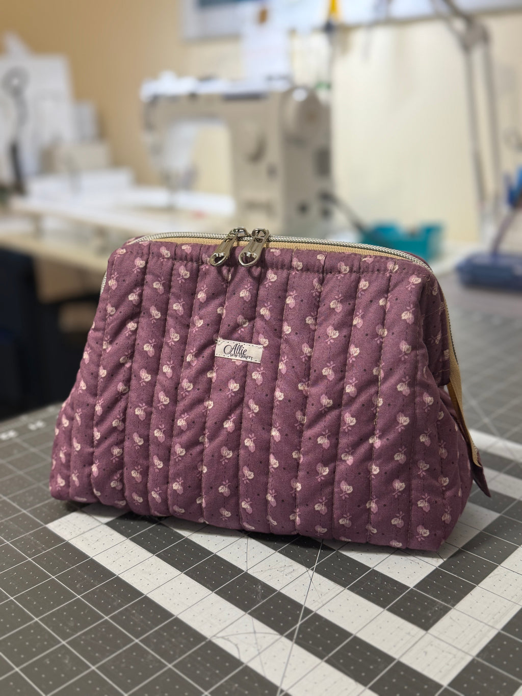 Purple quilted handbag with floral pattern on a checkered surface