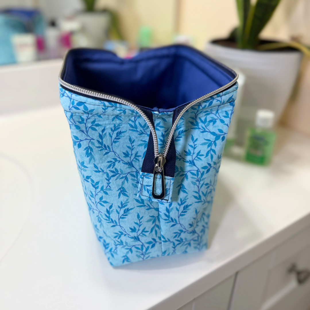 Blue floral-patterned bag with a zipper on a white surface.