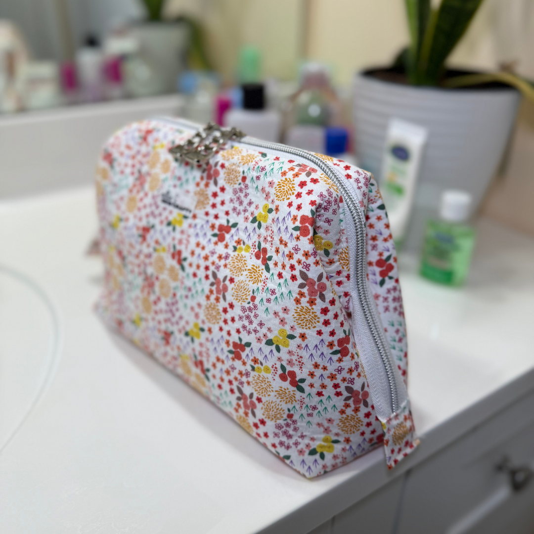 Floral patterned makeup bag on a bathroom counter with various items in the background.