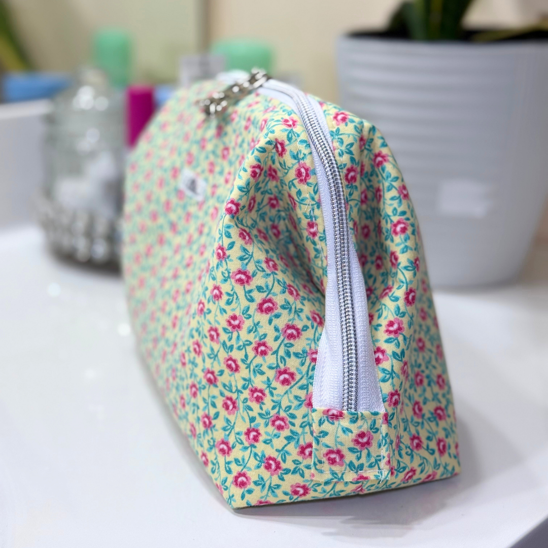 Floral patterned makeup bag on a white surface with blurred background