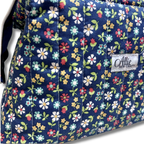 close up of quilting cotton fabric navy blue background with a colorful floral pattern of pink, yellow, white, and green flowers and Allie Sew Crafty in a white label.