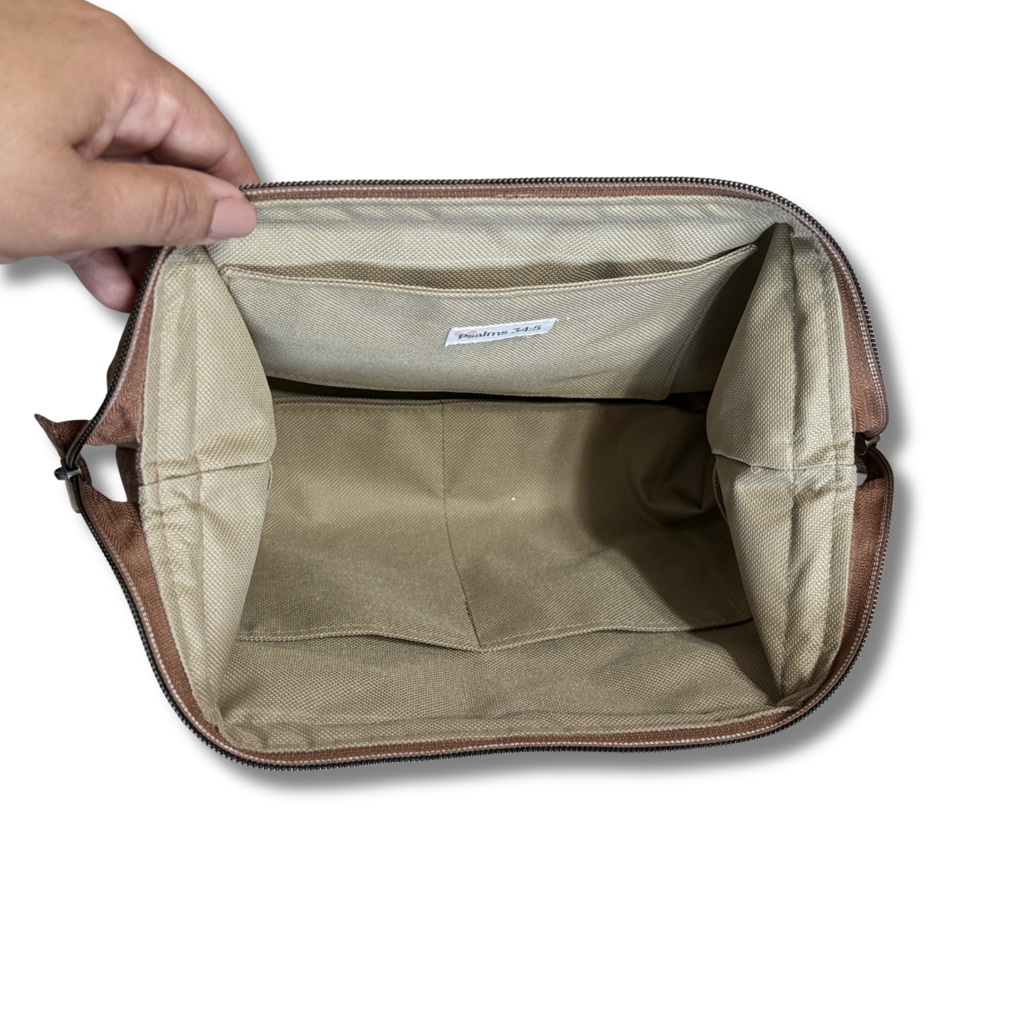 Hand opening a Solid Heathered Espresso Full View Pouch to show the tan water-resistant interior lining, interior pockets, and Psalm 34:5 tag