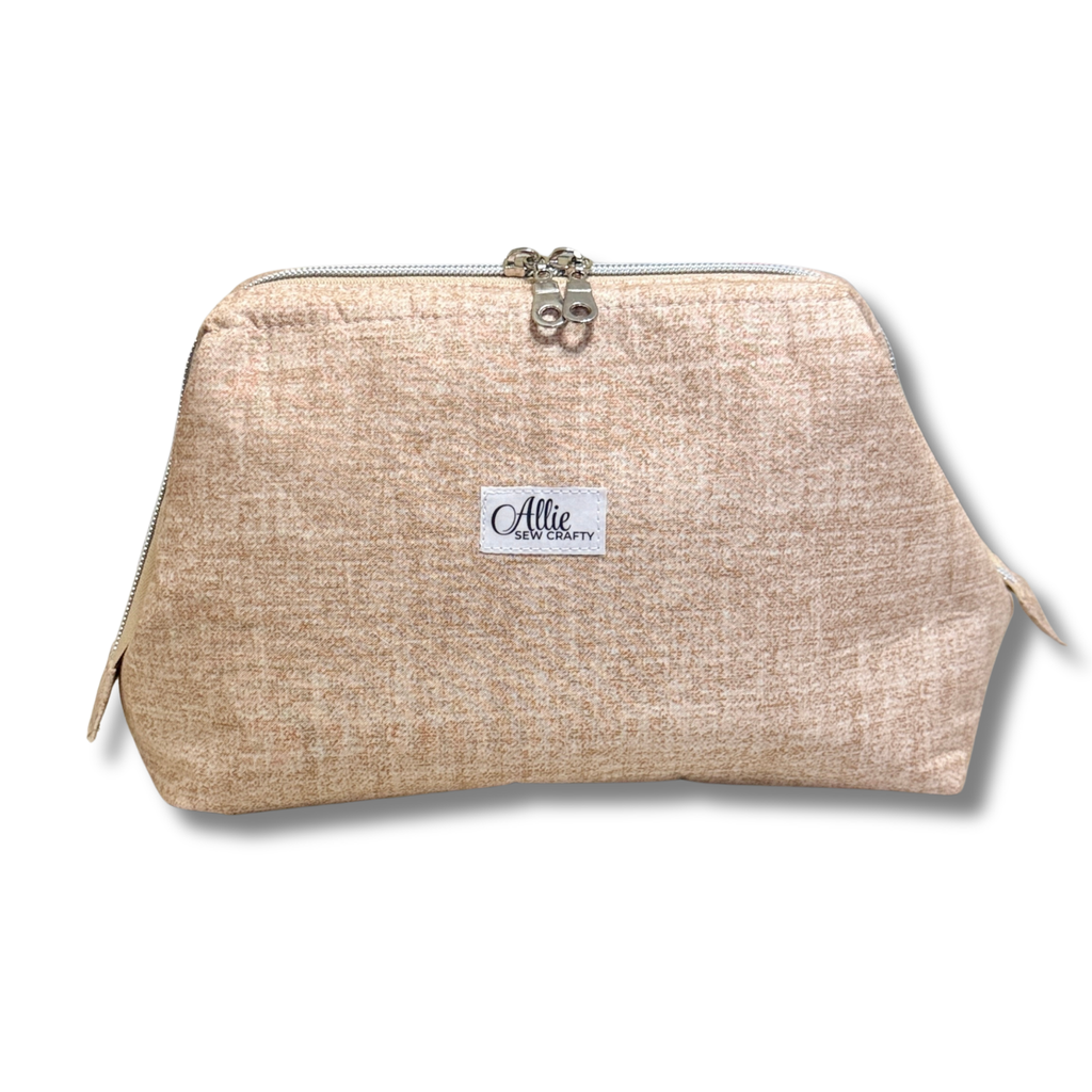 A textured beige cosmetic pouch with a silver zipper and a white brand label reading 'Allie Sew Crafty' in the center, shown on a white background.