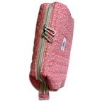 A pink quilted fabric pouch with a white floral pattern, featuring dual silver zippers and a small white brand label that reads 'Allie'