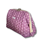 A quilted cosmetic pouch in a dusty purple fabric with a white floral pattern, featuring a cream-colored zipper and a small white brand label.