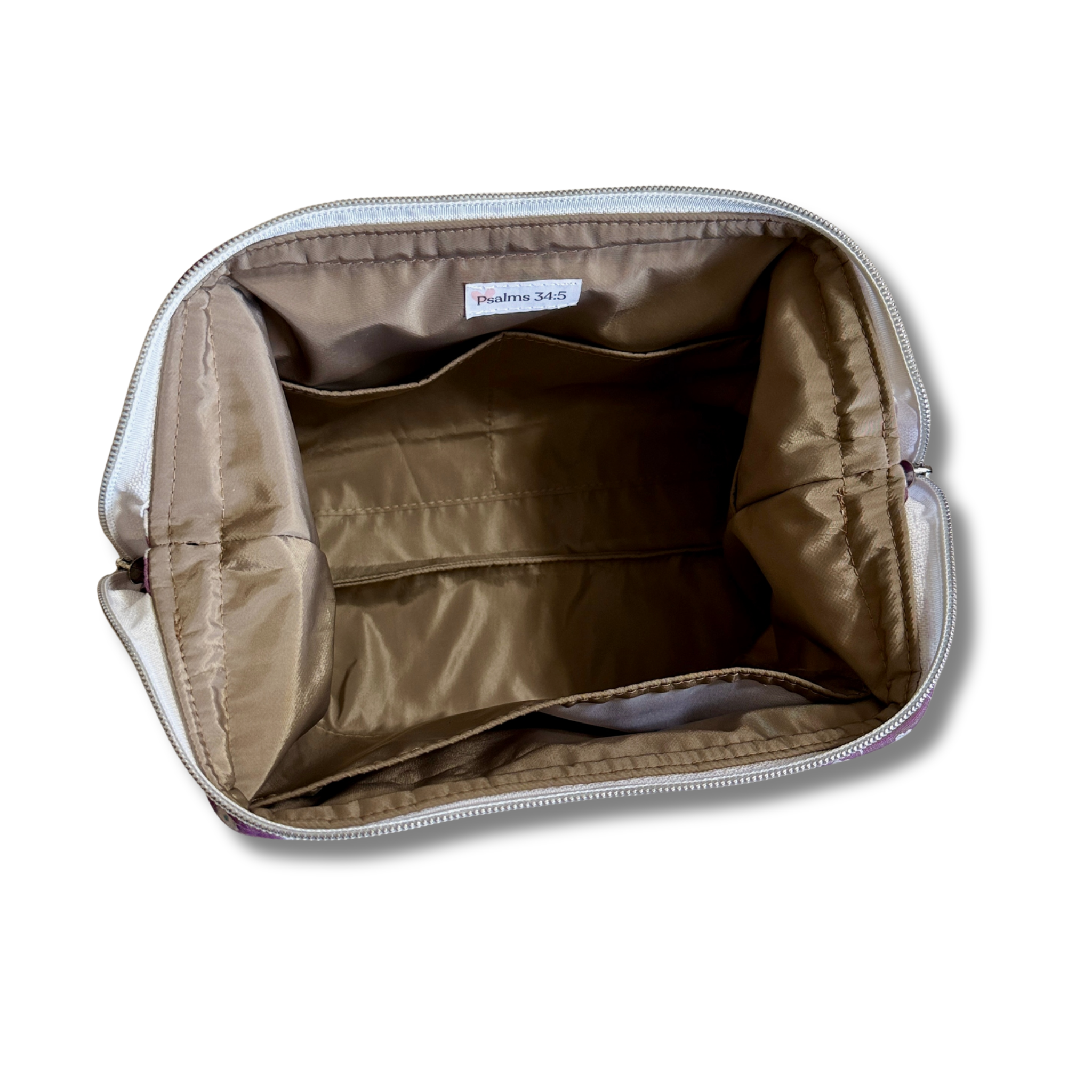 An open cosmetic bag or pouch shown from above, revealing a tan interior lining with zip-around closure and a small interior label that reads 'Peachy Sips'.