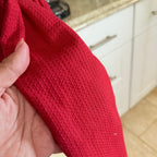 Red textured fabric held by a hand with a kitchen background