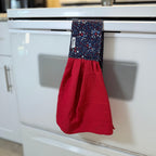Red kitchen towel with a blue polka dot design hanging on a white appliance.